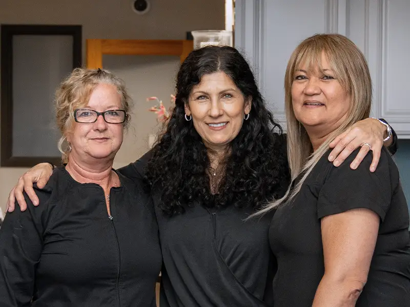 MFD Office team members smiling together with arms around each other at front desk