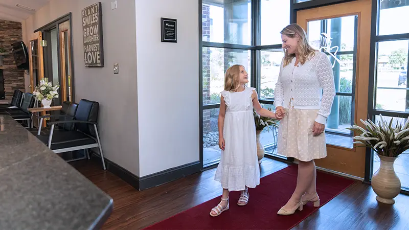 Mom and daughter walking into lobby for dental experience