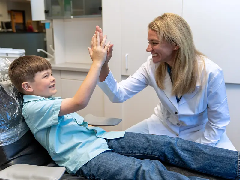 Dentist high-fiving pediatric patient